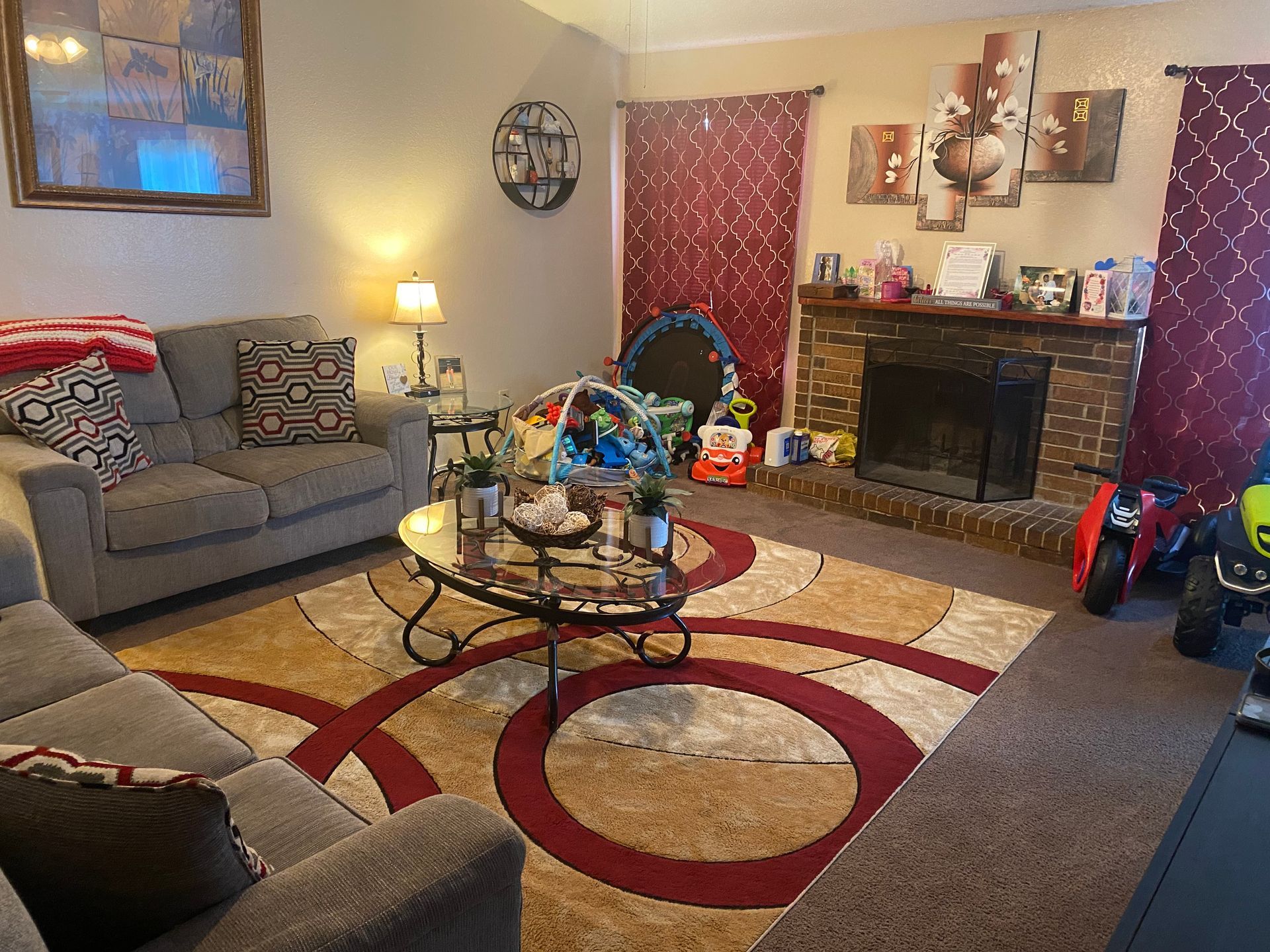 Living room with gray sofas, area rug, fireplace, and children's toys.