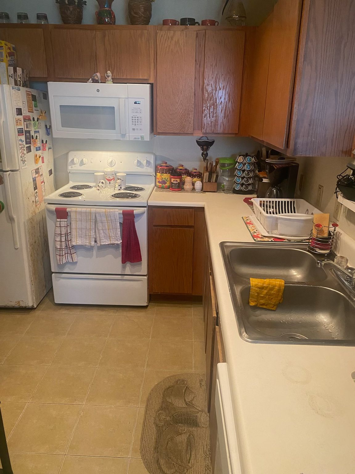 Kitchen with white appliances, wooden cabinets, and a double sink.