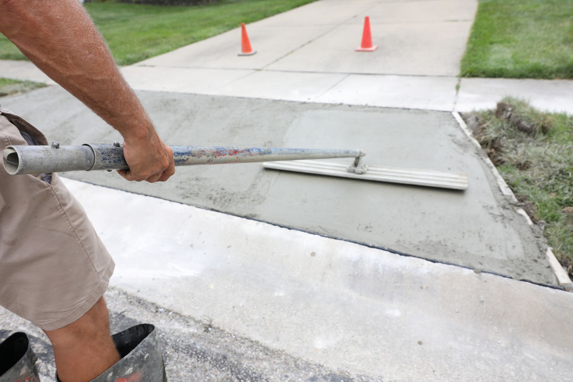 Person using a concrete float to smooth a fresh concrete driveway.