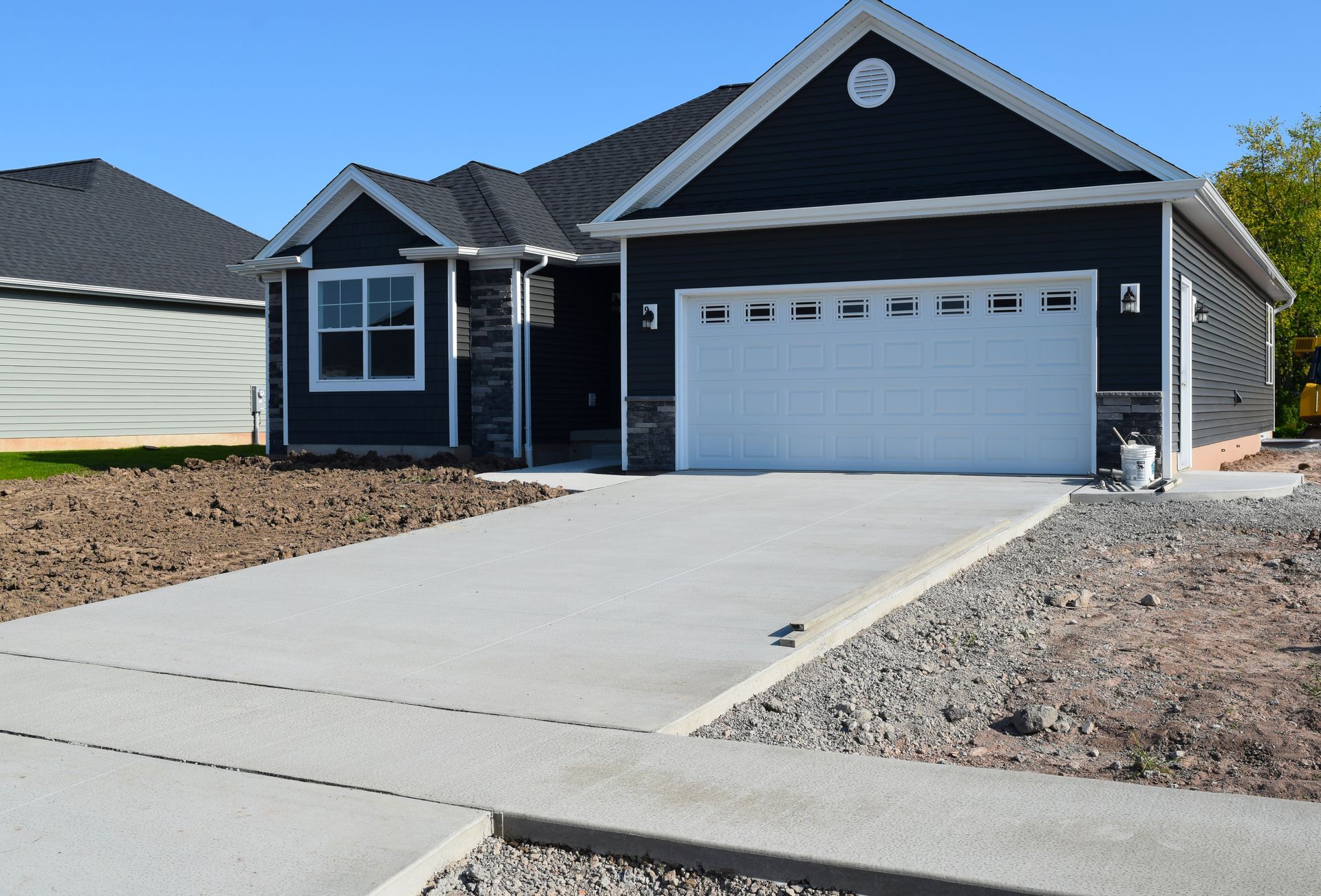 New house with gray concrete driveway and sidewalk, blue siding, and white garage door.