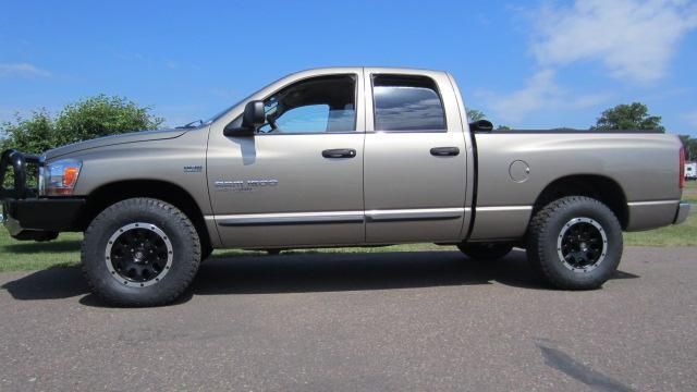 Silver pickup truck in side view parked on pavement with trees in the background