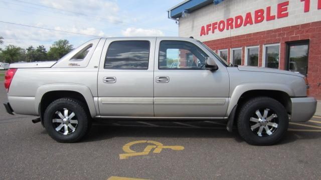 Silver crew cab pickup truck parked outside an affordable dealership.