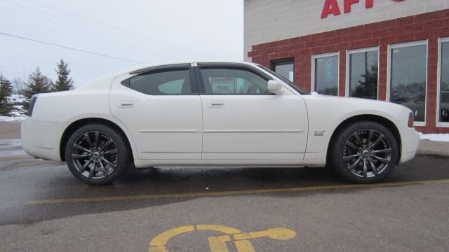 White two-door coupe parked outside an auto service building on a wet lot