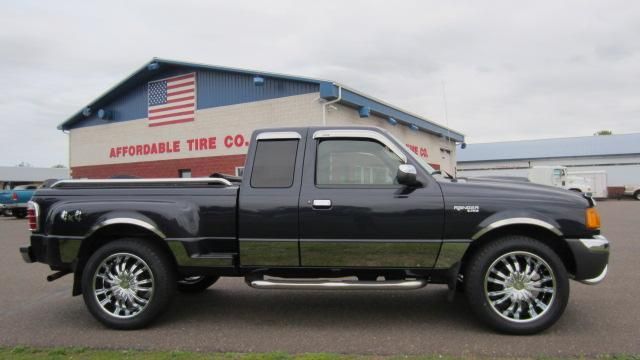 Black pickup truck parked outside a tire shop under cloudy skies