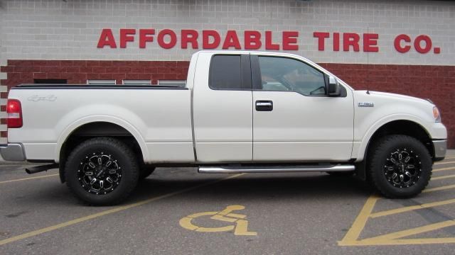 White pickup truck parked side-on in front of Affordable Tire Co. sign on a brick wall.