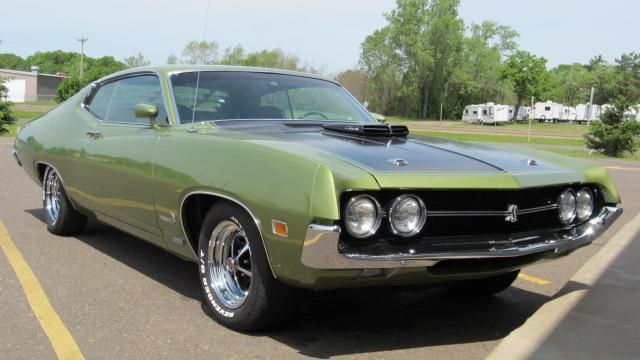 Green classic muscle car parked outdoors on a sunny day