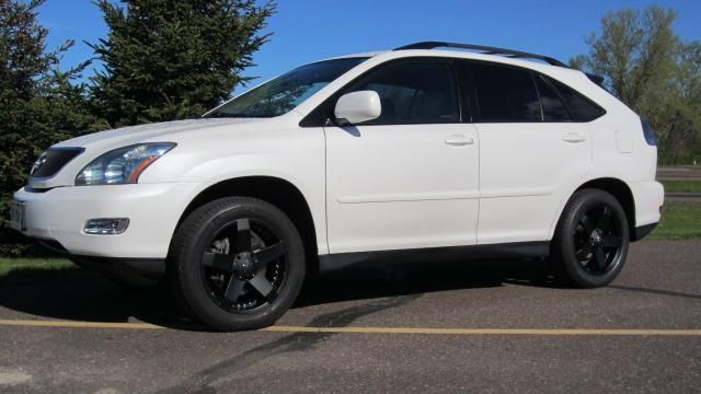 White SUV with black wheels parked in a lot under a clear sky