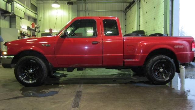 Red pickup truck parked inside a garage, with wet floor and industrial lighting.