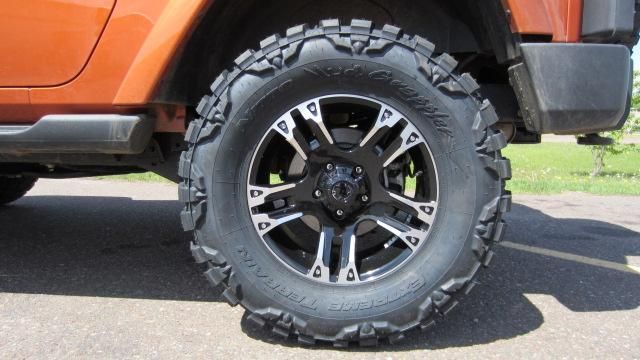 Orange off-road vehicle with black wheel and rugged tire on pavement