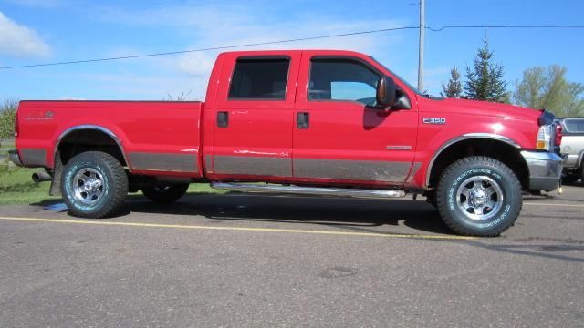 Red pickup truck with extended cab parked on a road under a clear blue sky