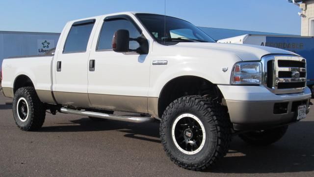 White lifted Ford pickup truck parked outdoors on a lot, side view with off-road tires