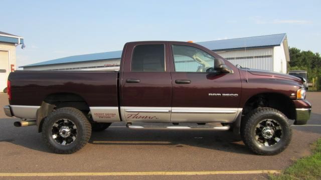 Maroon and tan pickup truck parked beside a building, side view.