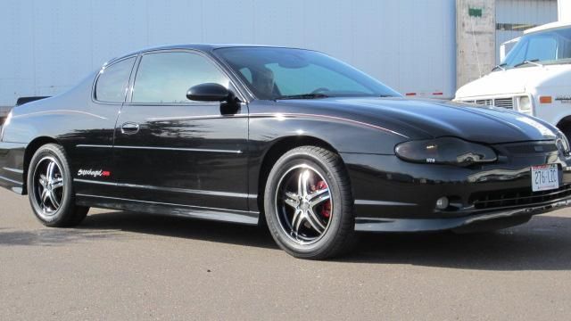 Black sports coupe parked outdoors on pavement, side view.