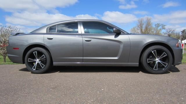 Gray sports sedan parked on a road under a blue sky
