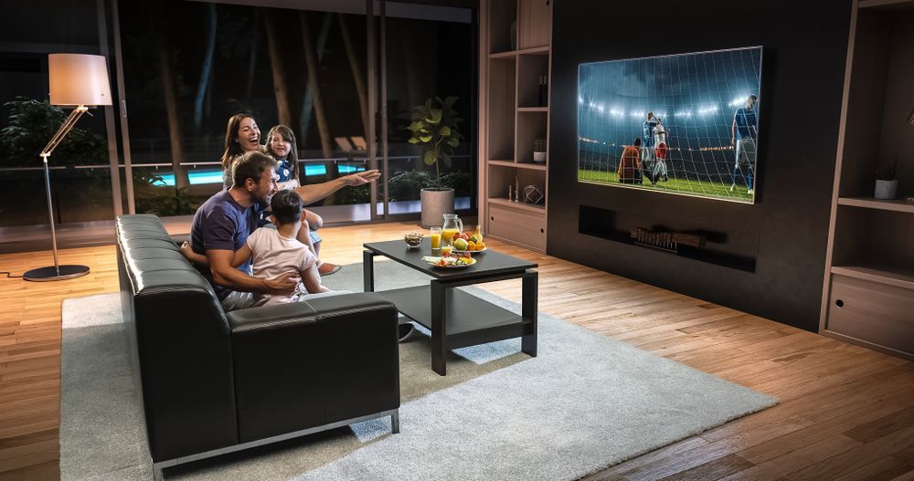 A Family Is Sitting On A Couch Watching A Football Game On A Television — Craig's TV/Antenna Services In Lake Macquarie, NSW