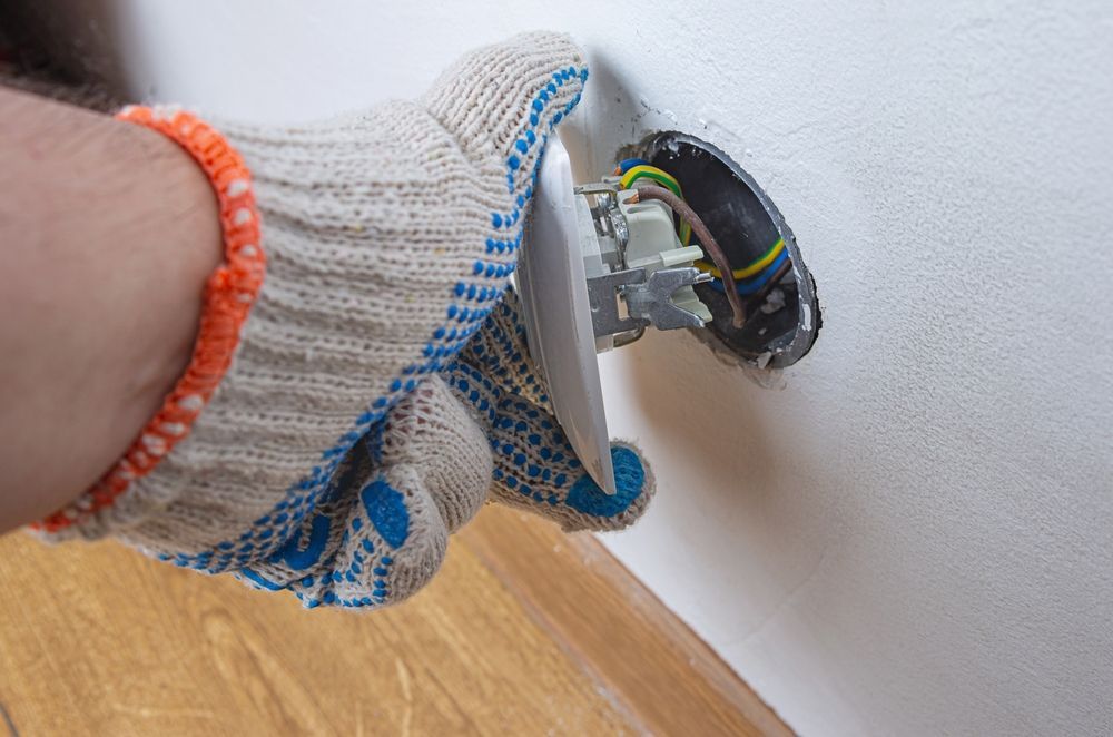 A Person Is Installing A Light Switch On A Wall — Craig's TV/Antenna Services In Cardiff, NSW
