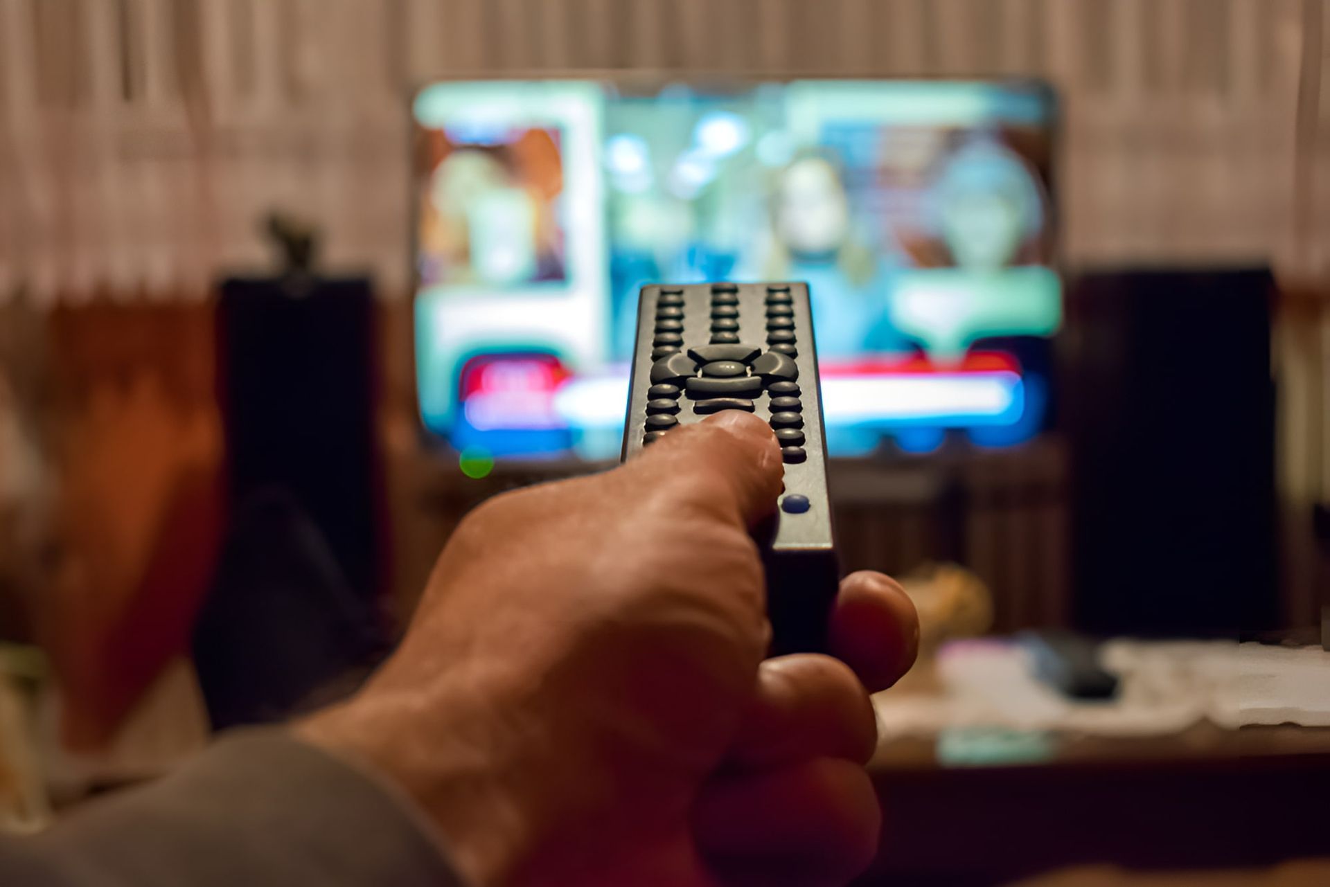 A Person Is Holding A Remote Control In Front Of A Television — Craig's TV/Antenna Services In Cardiff, NSW