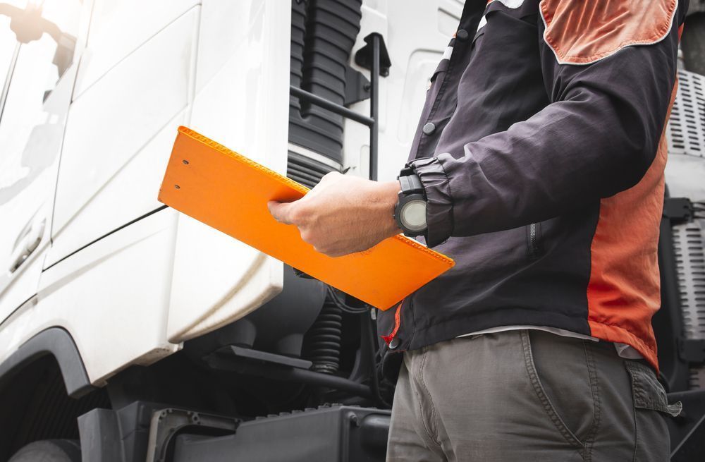 A Man in Work Clothes Holding Orange Clipboard — Aust. Advanced Trailer Sales & Service in Katherine, NT