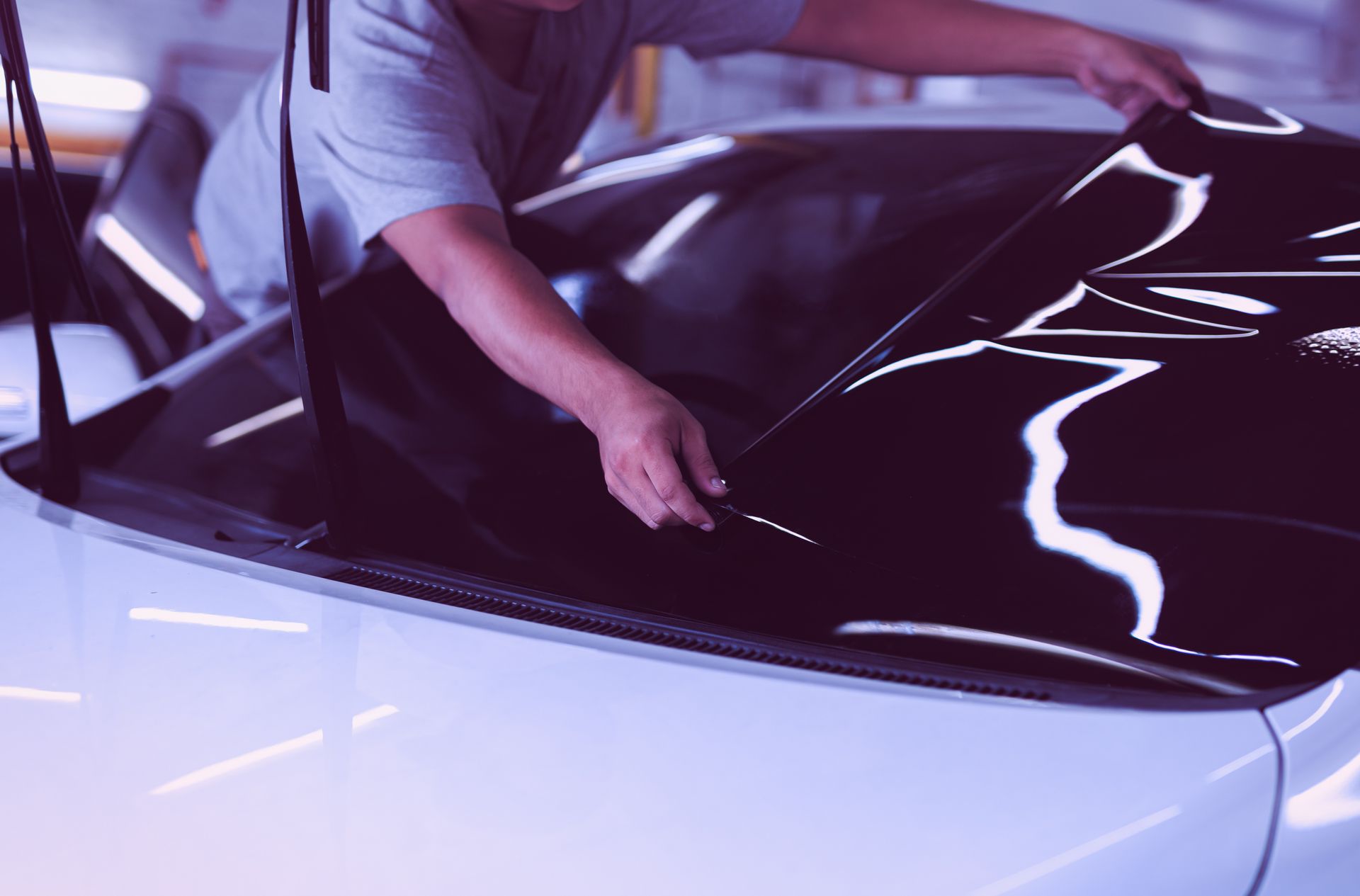 Car specialist applying tinting foil on a car window in auto service. 