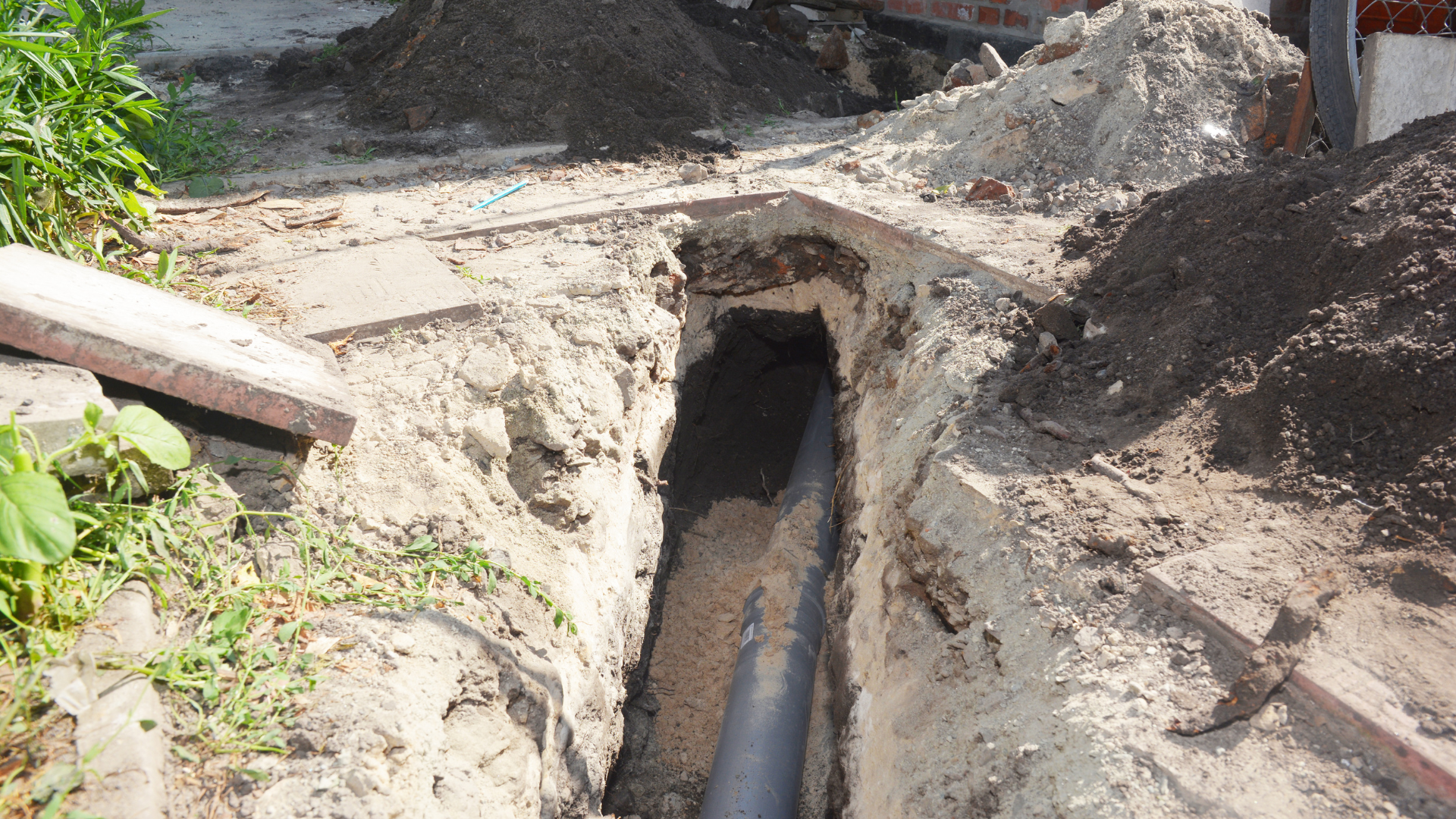 Open trench with exposed pipe and muddy dirt at a construction site