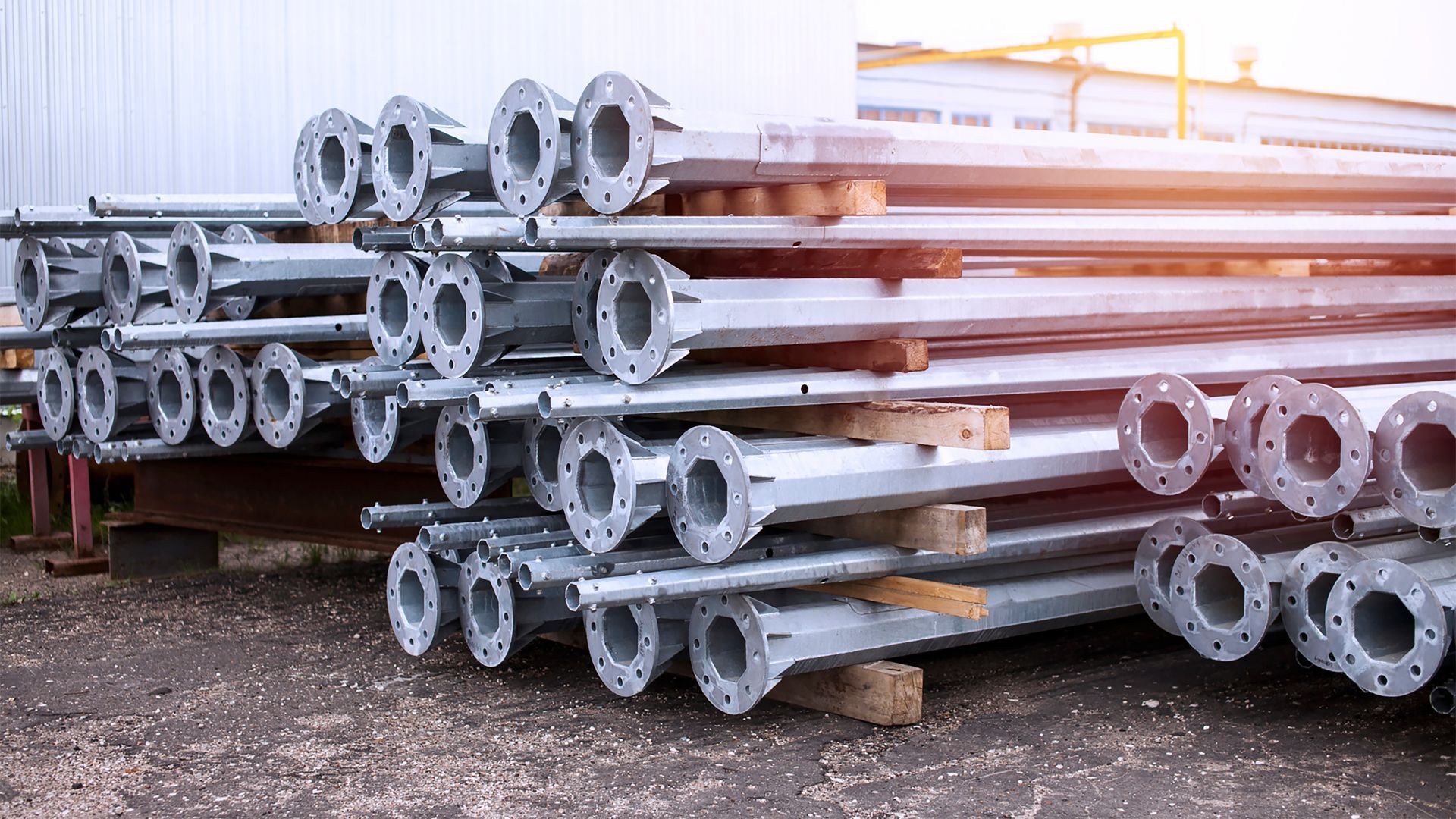 Metal service center with stacked galvanized steel poles ready for distribution