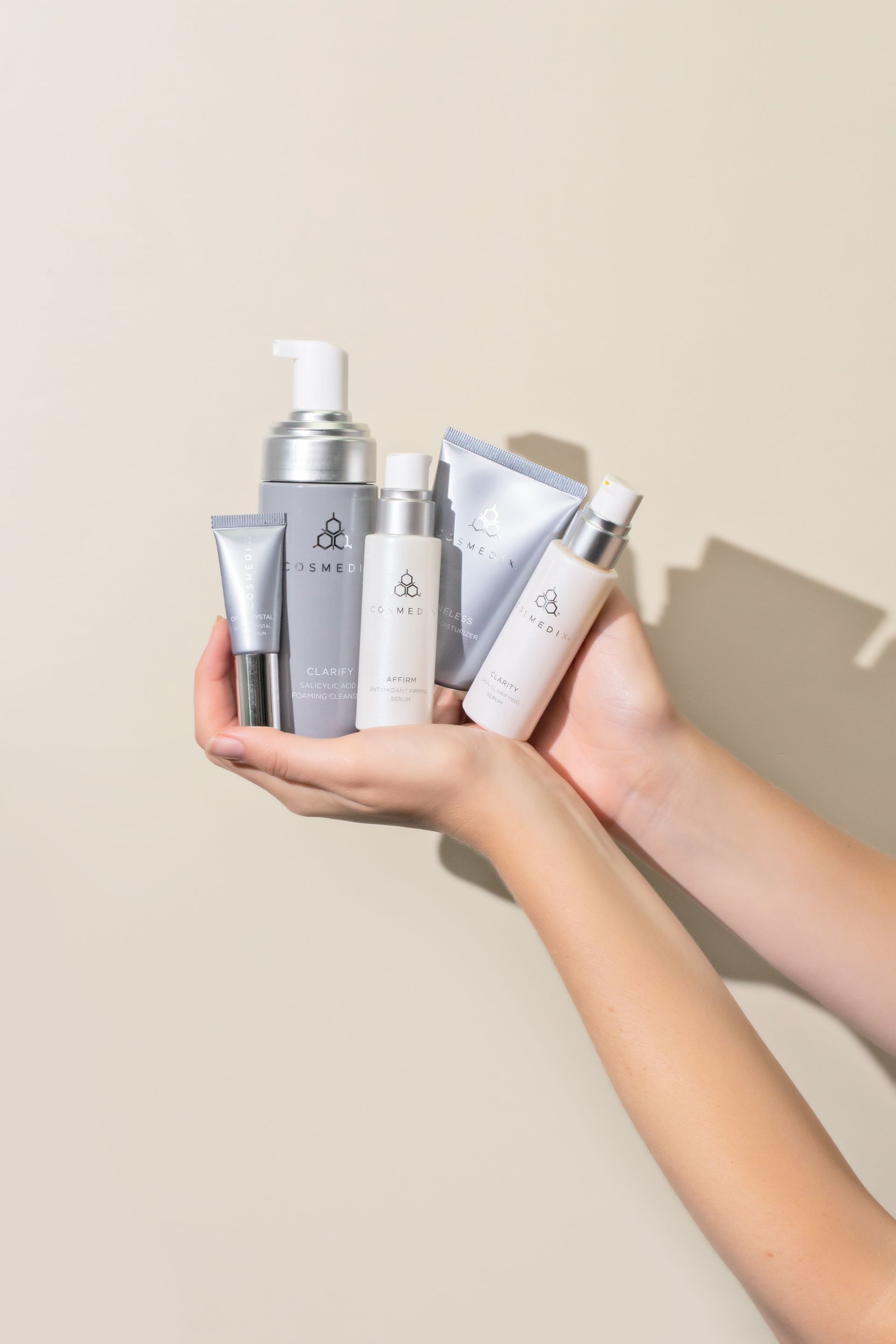 Woman holding an assortment of COSMEDIX professional skincare products, highlighting personalized ho