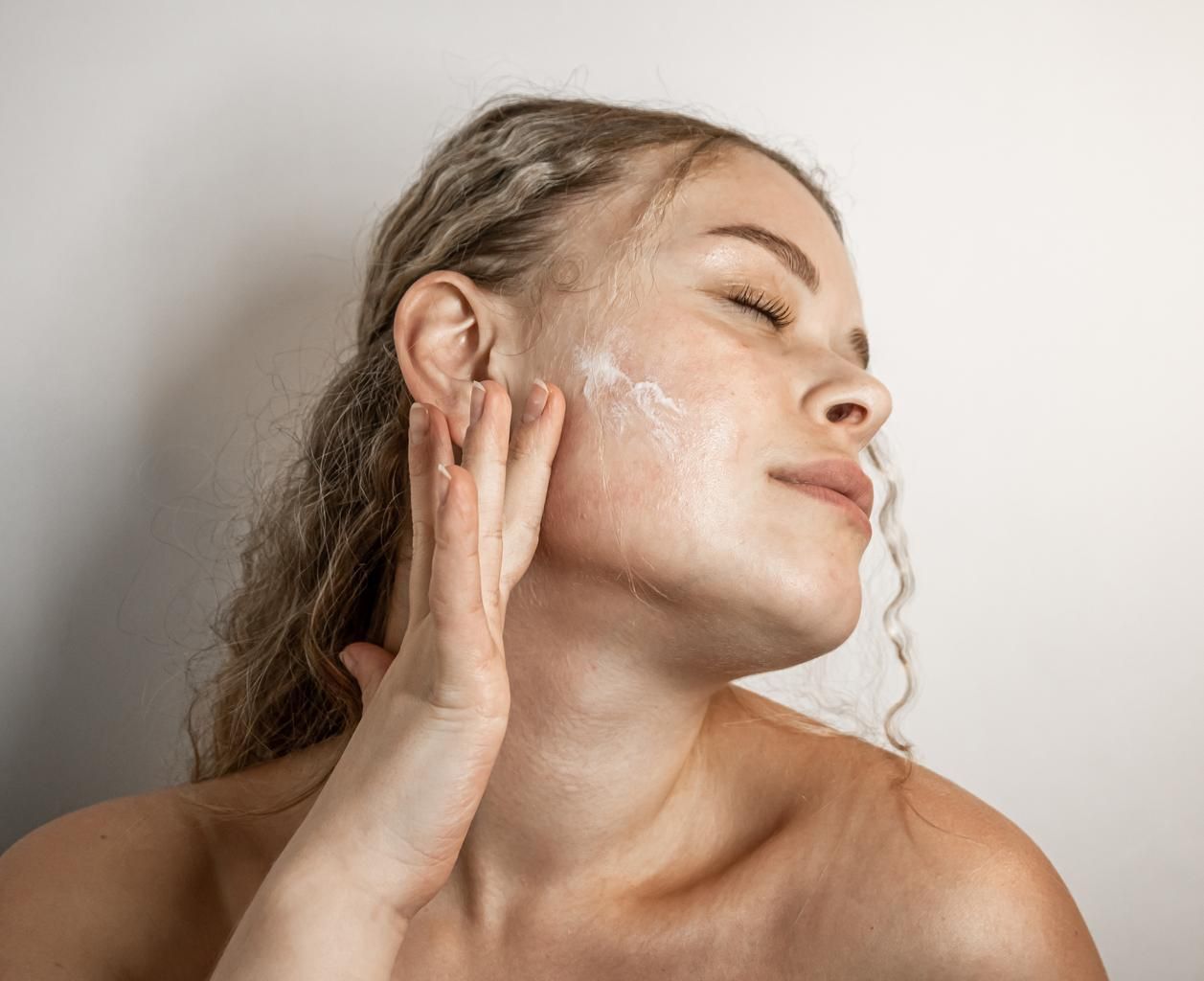 Apply Moisturizer helps retain barrier protection Woman applying moisturizer on her skin contemplating her skin care products and facial treatments.