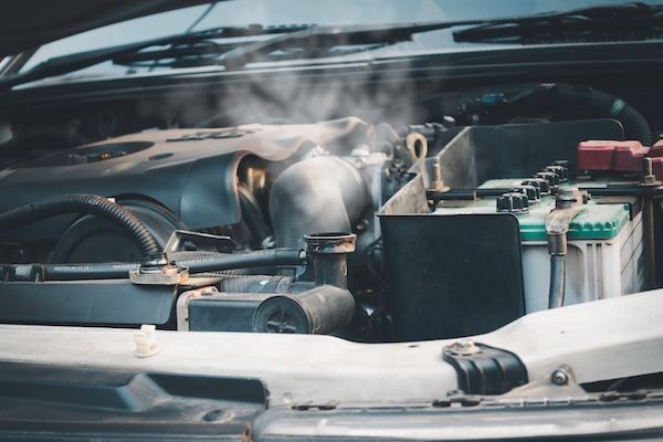Open car hood showing engine components with visible steam or smoke | Allen's Automotive