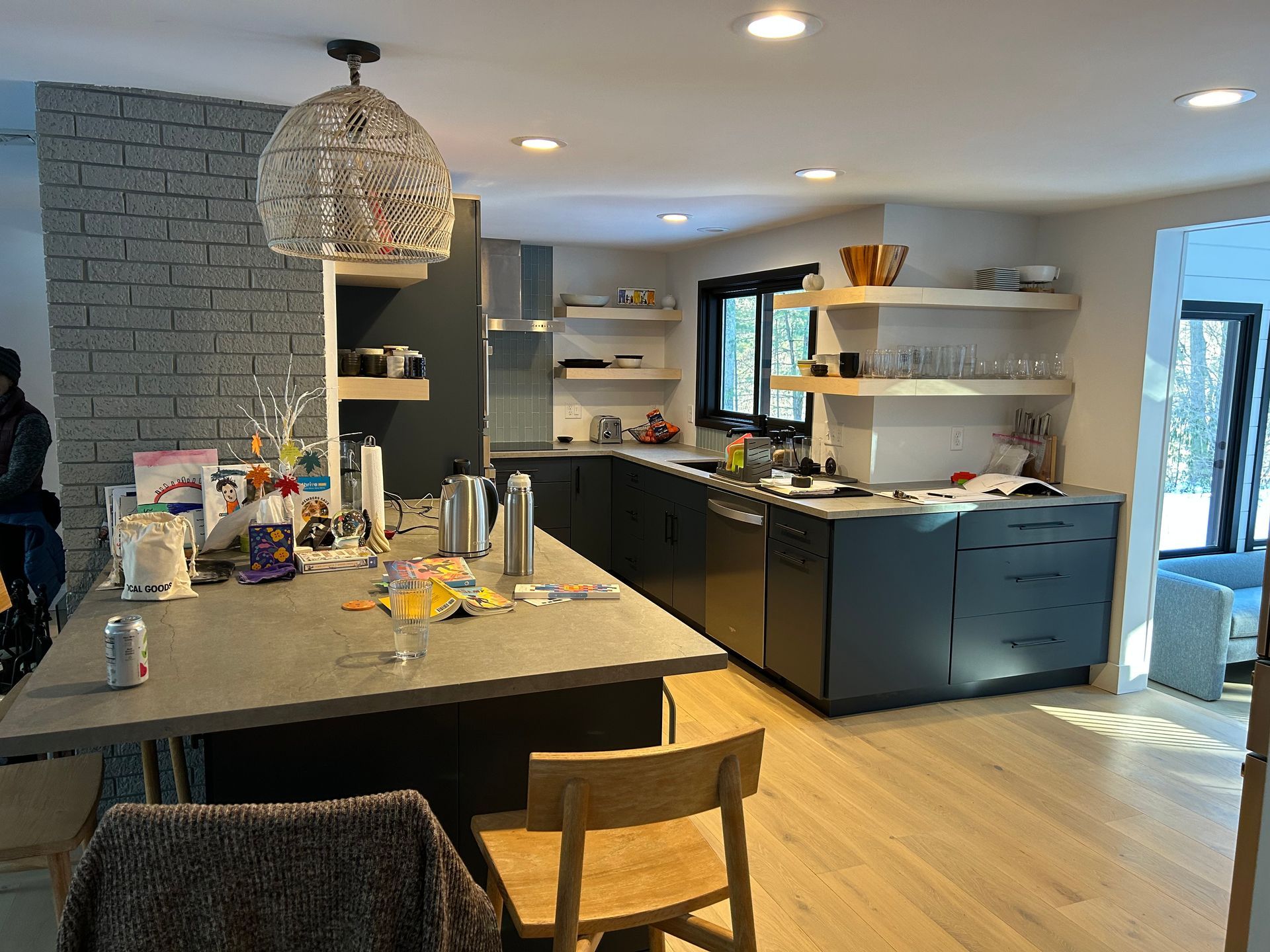 Modern kitchen with dark cabinets, open shelving, gray island, and wood floors.