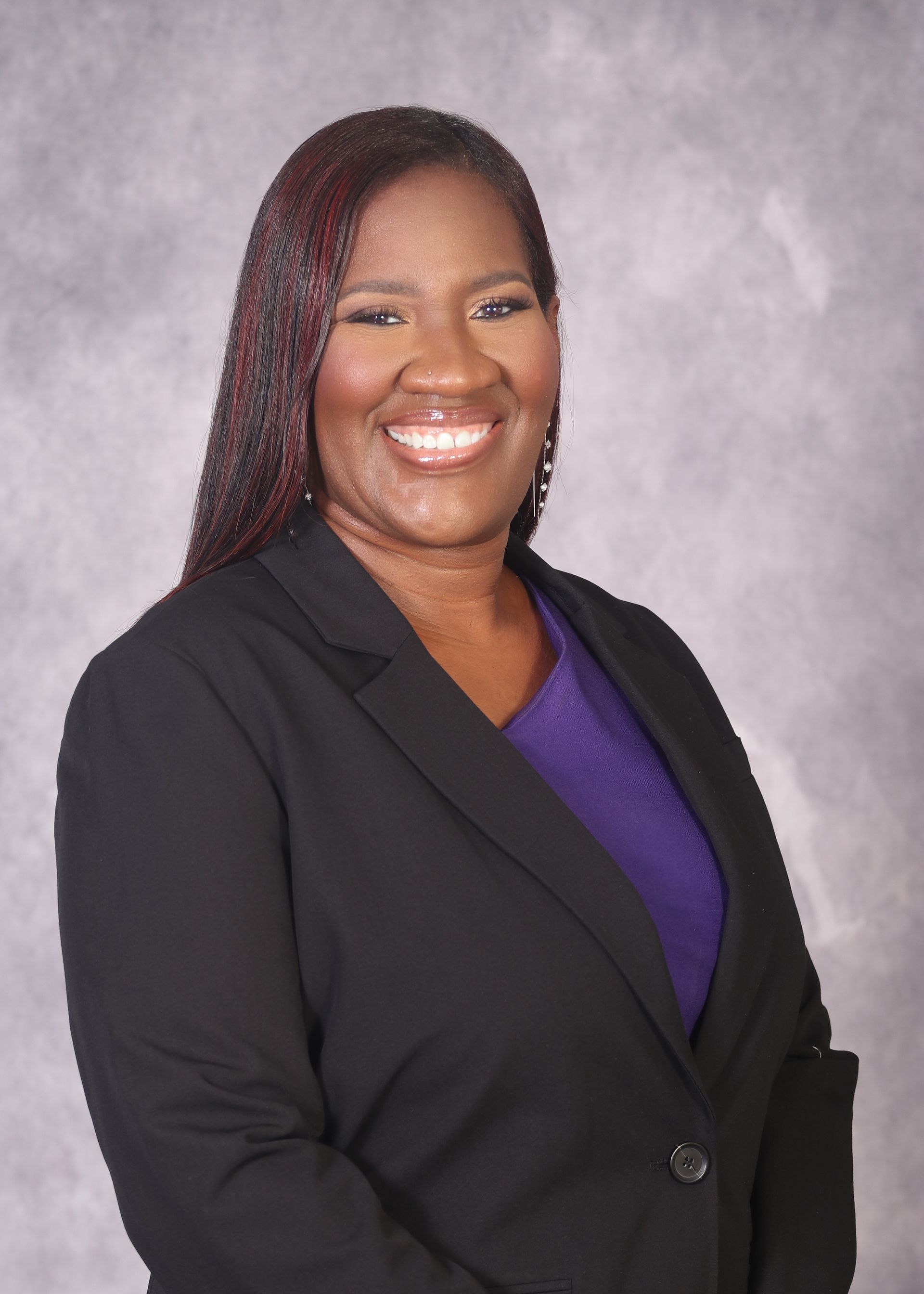 Teneisha Frank-Wright in a black jacket and purple shirt smiles for the camera