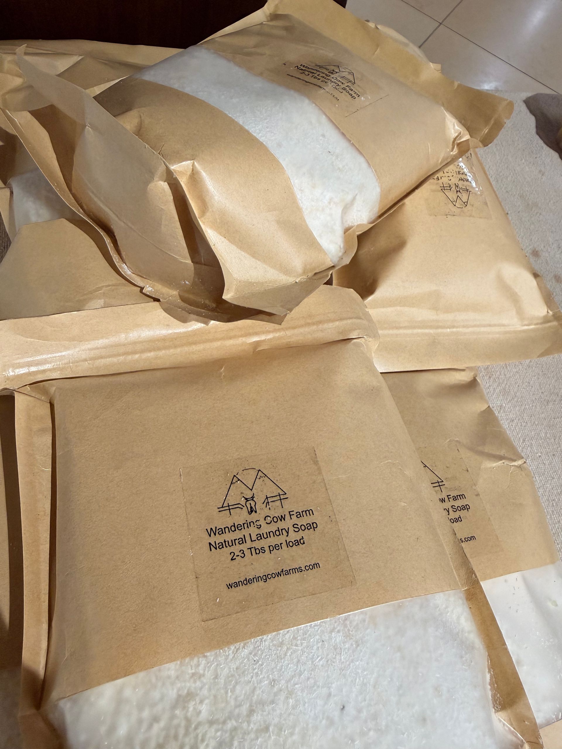 Stack of beige paper pouches with white contents, arranged on a textured surface.