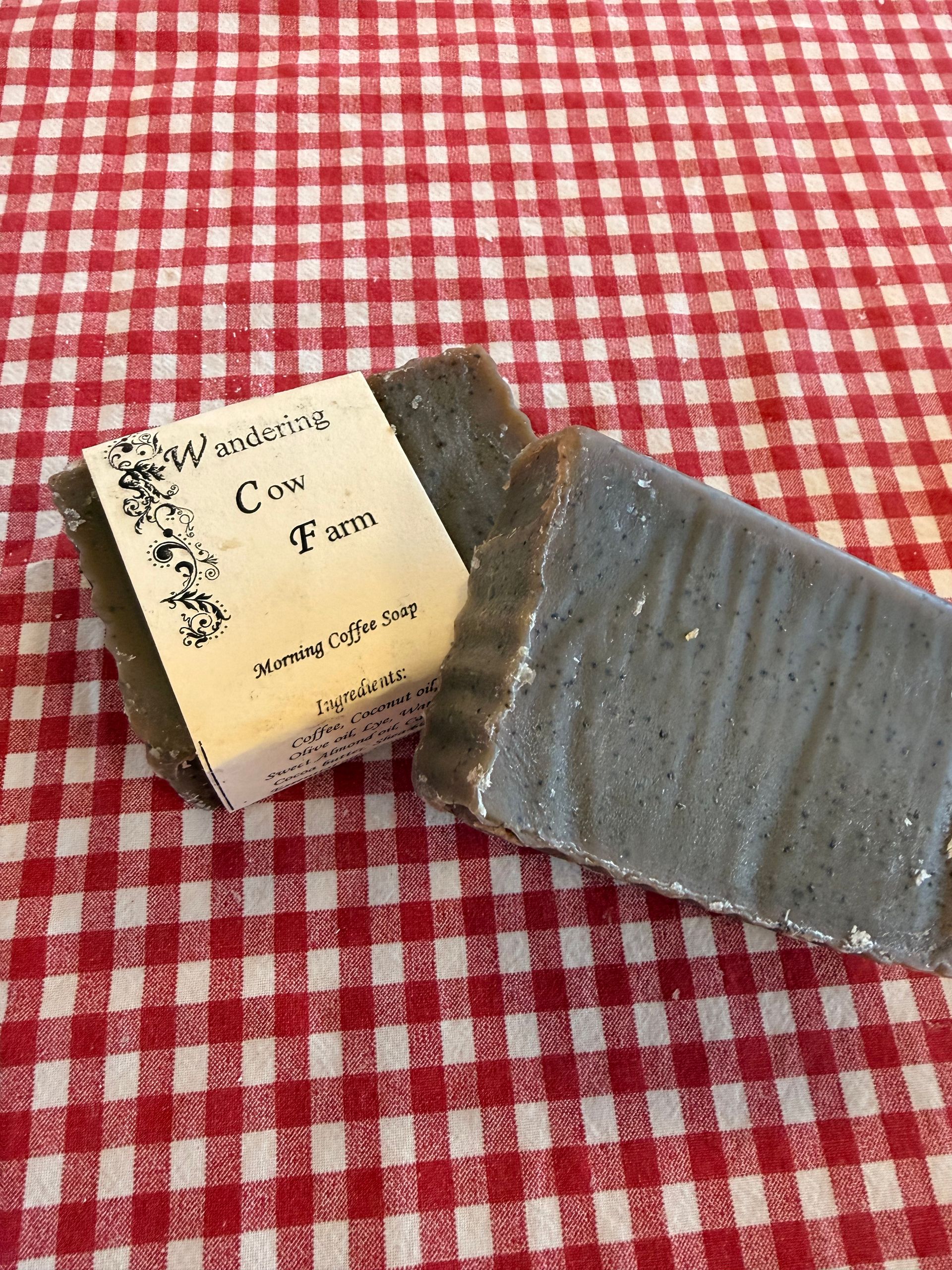 Bar of gray soap beside its packaging on a red-and-white checkered tablecloth