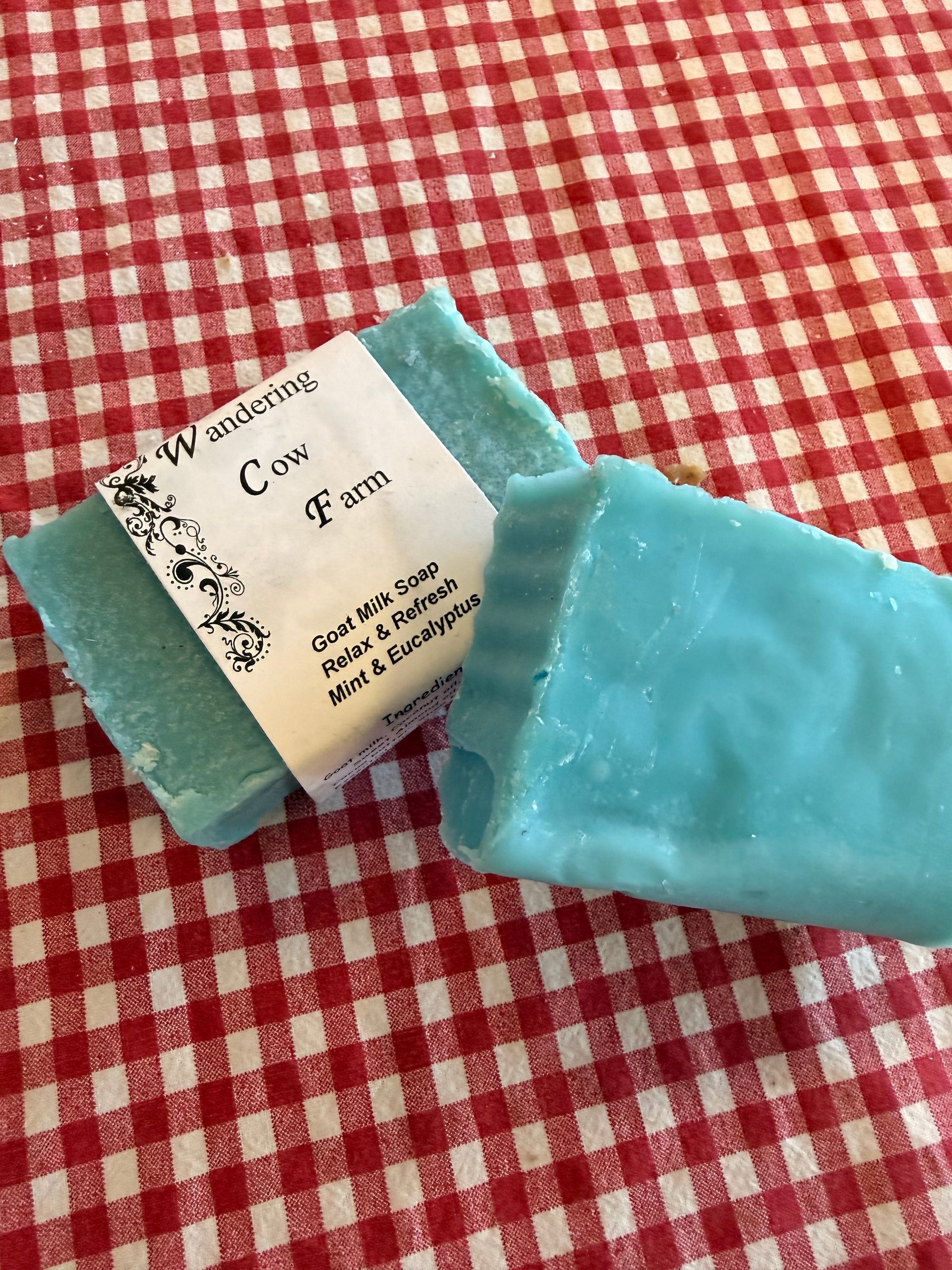 Blue soap bars on a red-and-white checkered tablecloth, one showing a label.