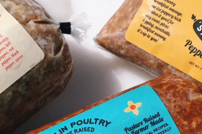 Three packages of ground meat with colorful labels arranged on a white surface.