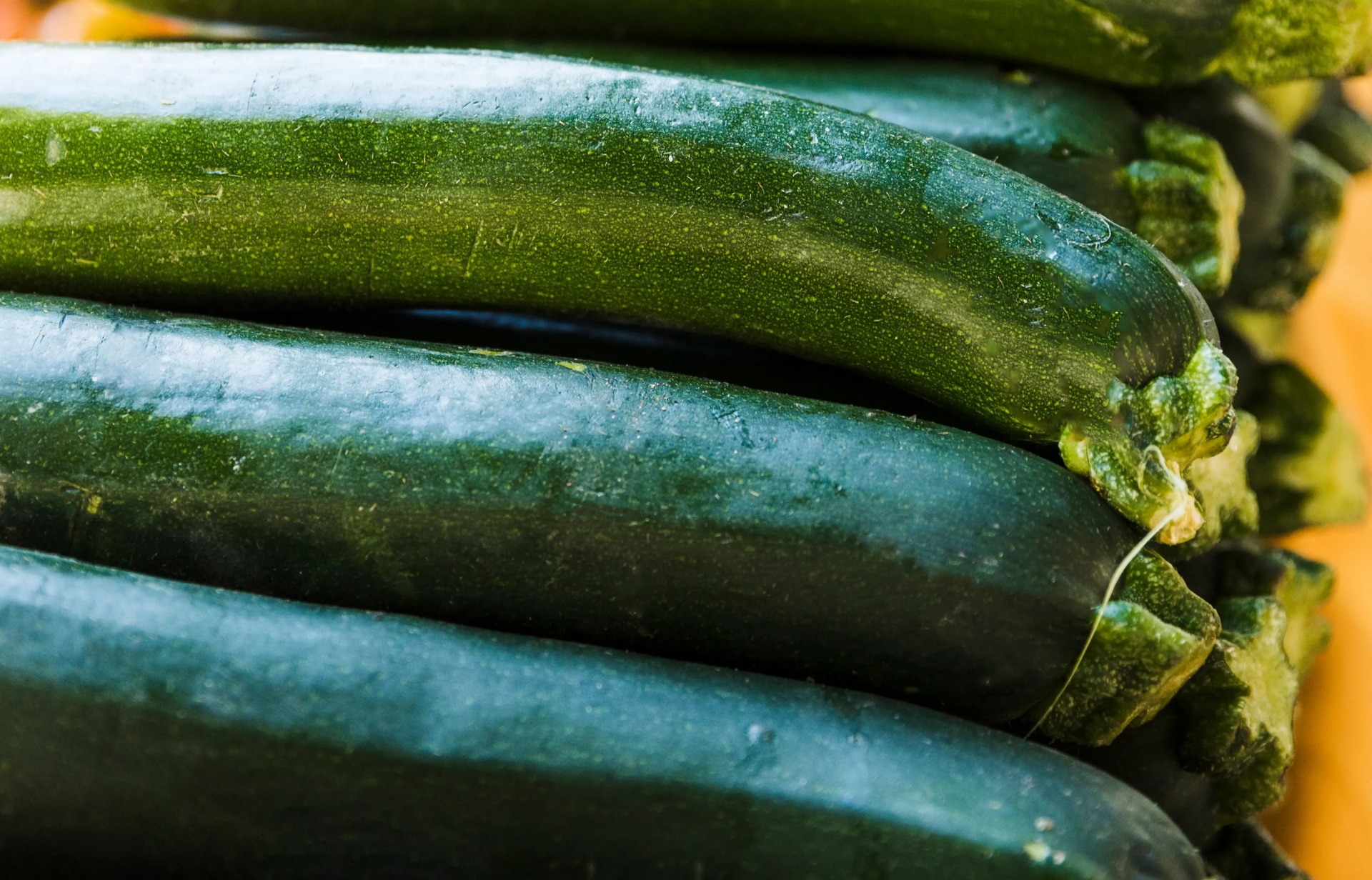 A close-up of a stack of dark green zucchinis.