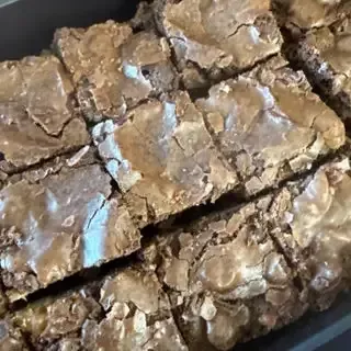 A tray of freshly baked, square-cut chocolate brownies with shiny, crinkled tops.
