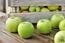 Several bright green Granny Smith apples arranged on a rustic wooden surface.