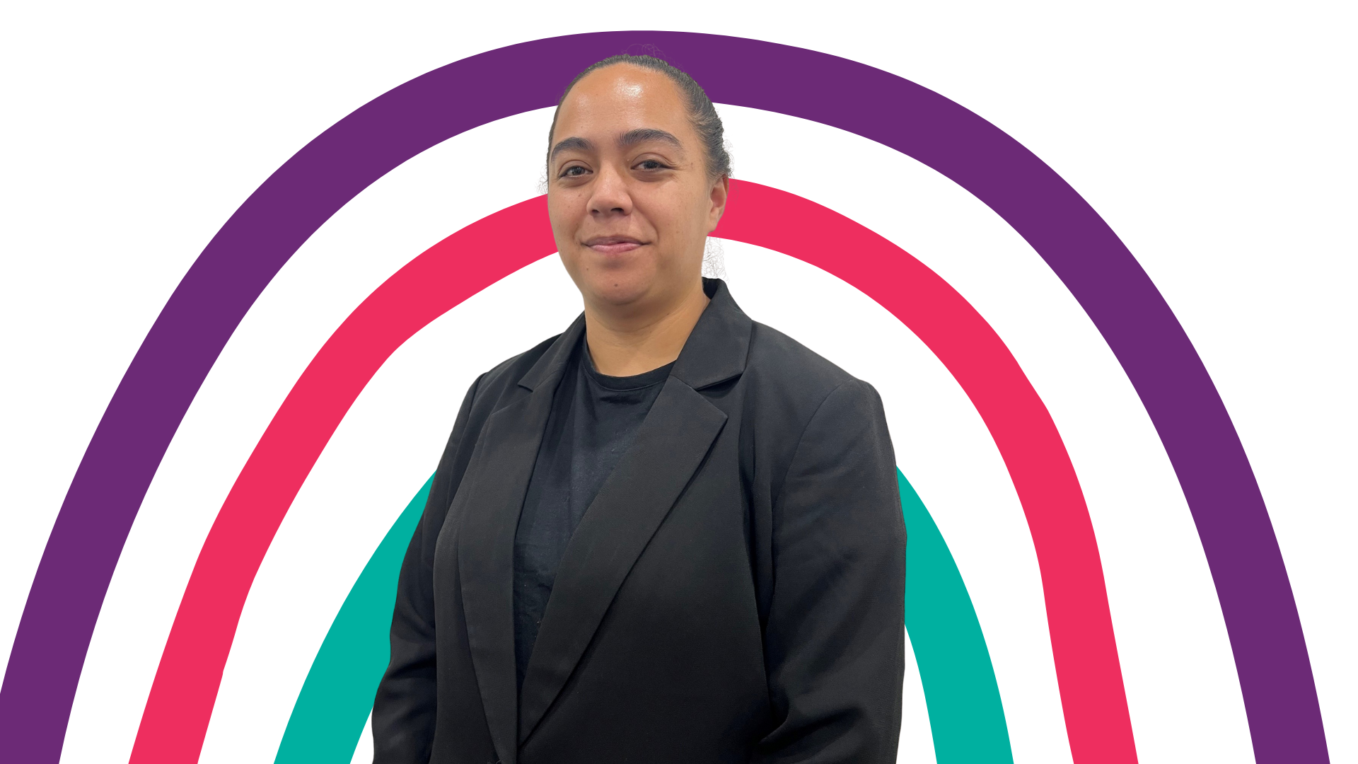 A woman in a suit is standing in front of a rainbow.