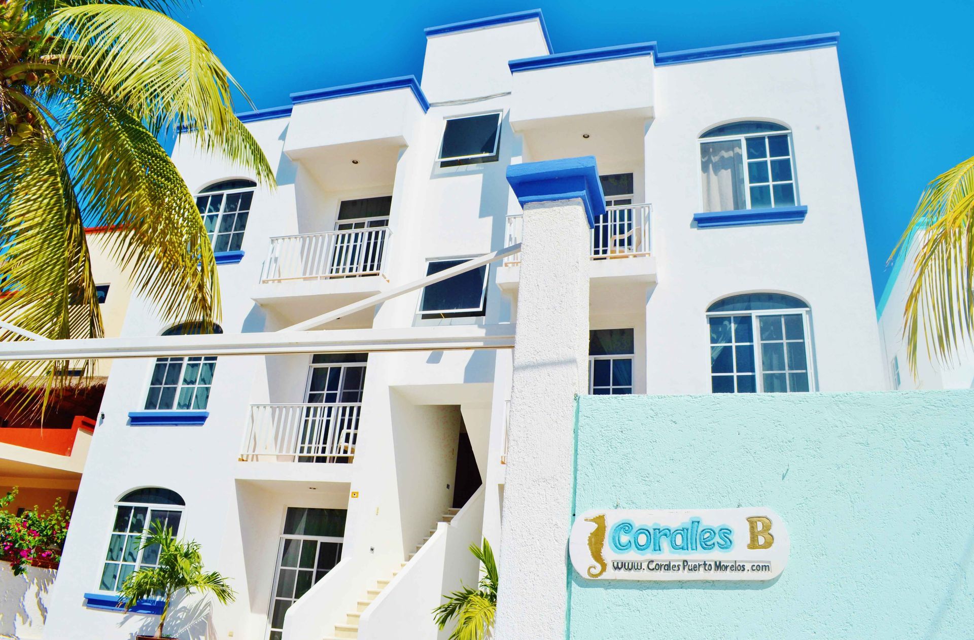 White multi-story building with blue trim, balconies, and a sign that reads “Cardias B”.