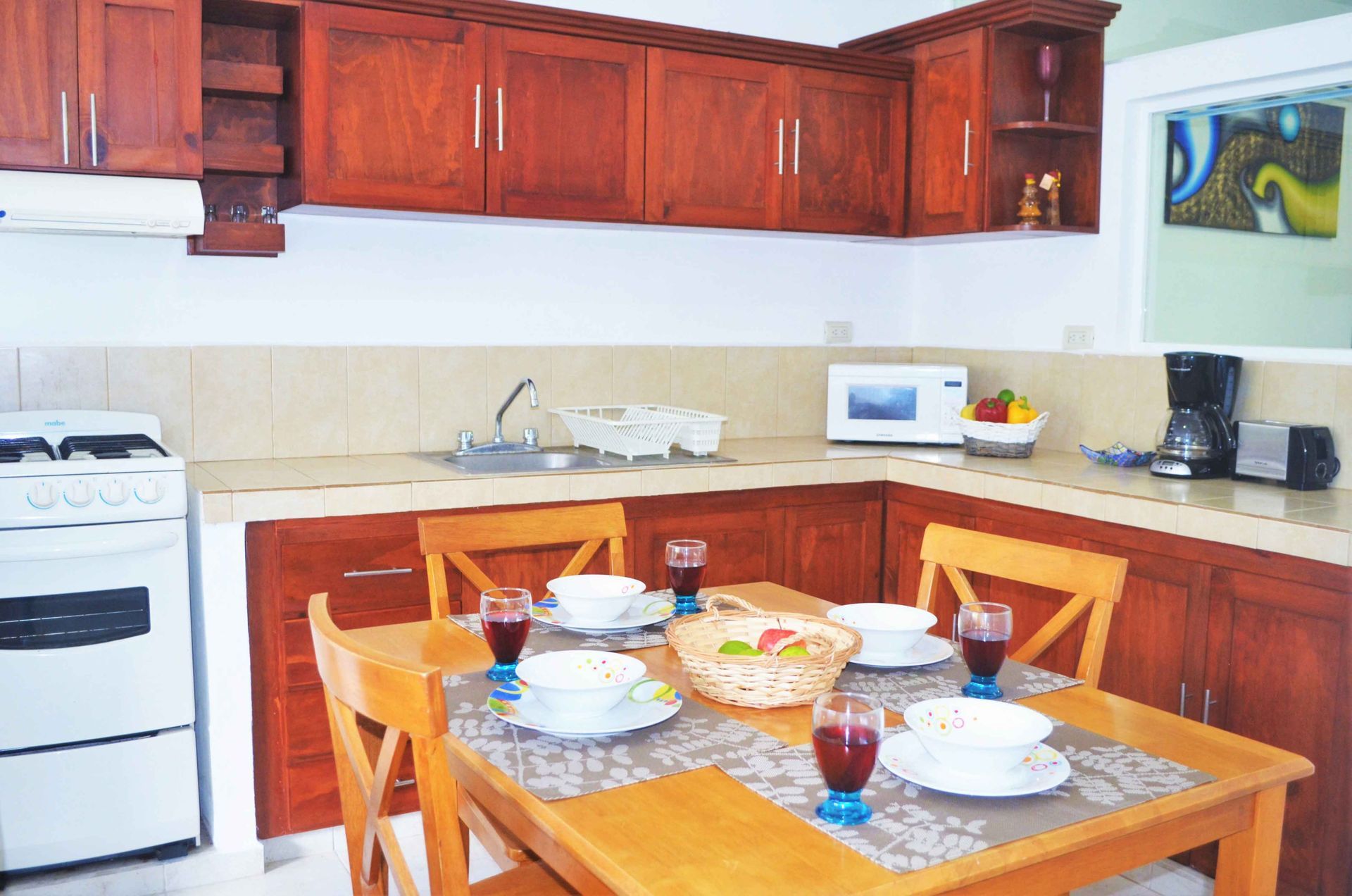 Kitchen with wooden cabinets, a table set for four, and appliances like a stove and microwave.