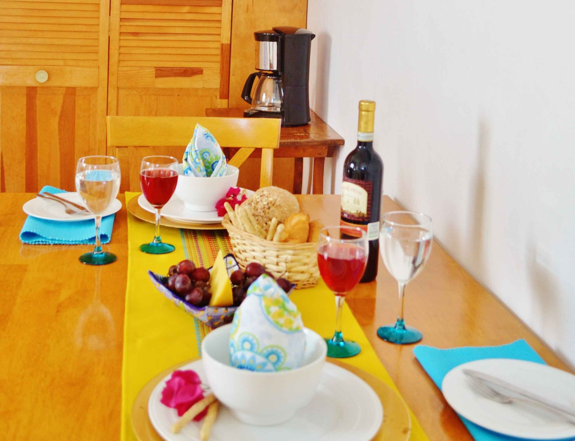 Mesa puesta para una comida: vino, pan, fruta y servilletas.