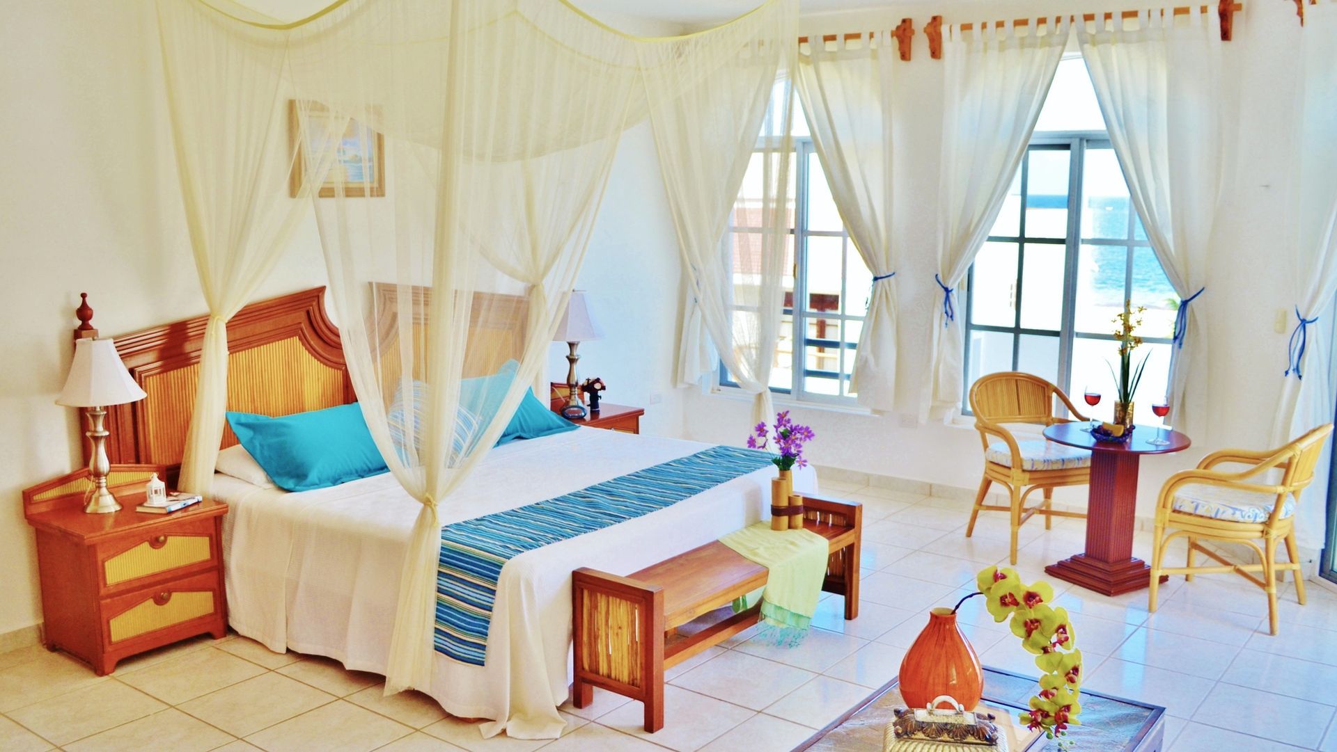 Bedroom with canopy bed, nightstands, and window seating. White walls, wood furniture, and soft colors.