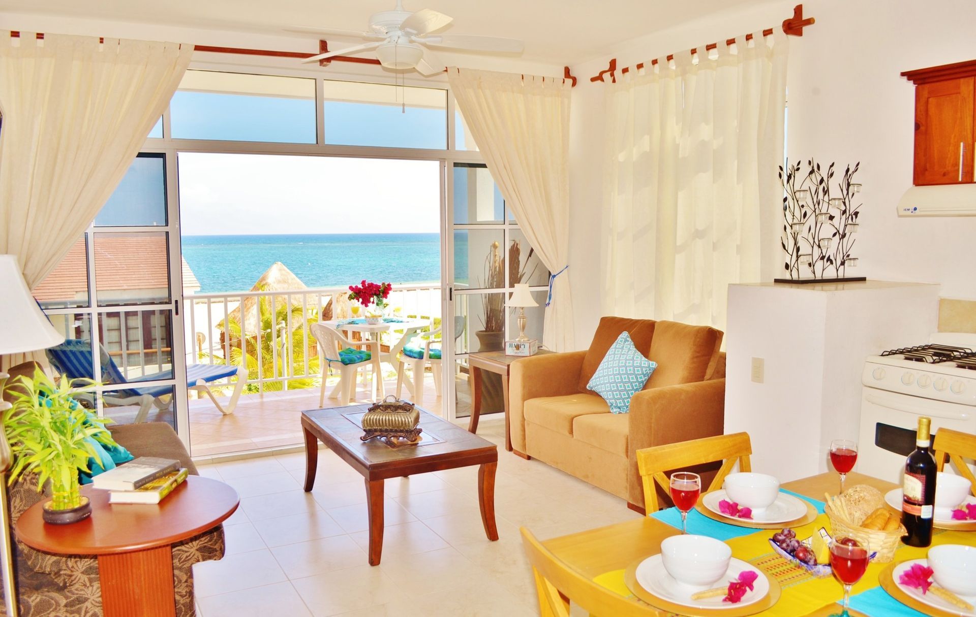 Living room with balcony overlooking ocean view, with table set for meal.