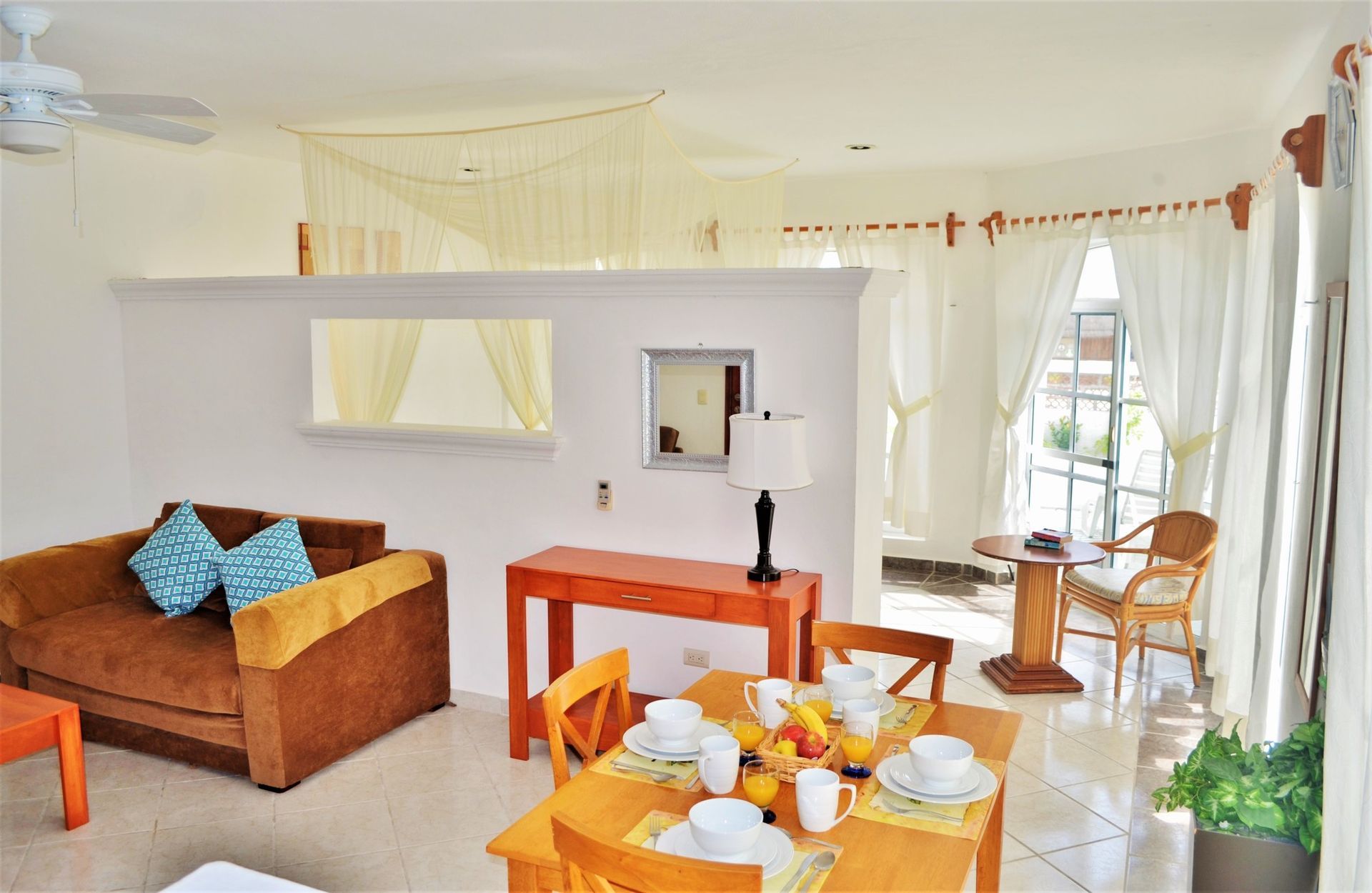 Bright living room with couch, dining table, and open window.