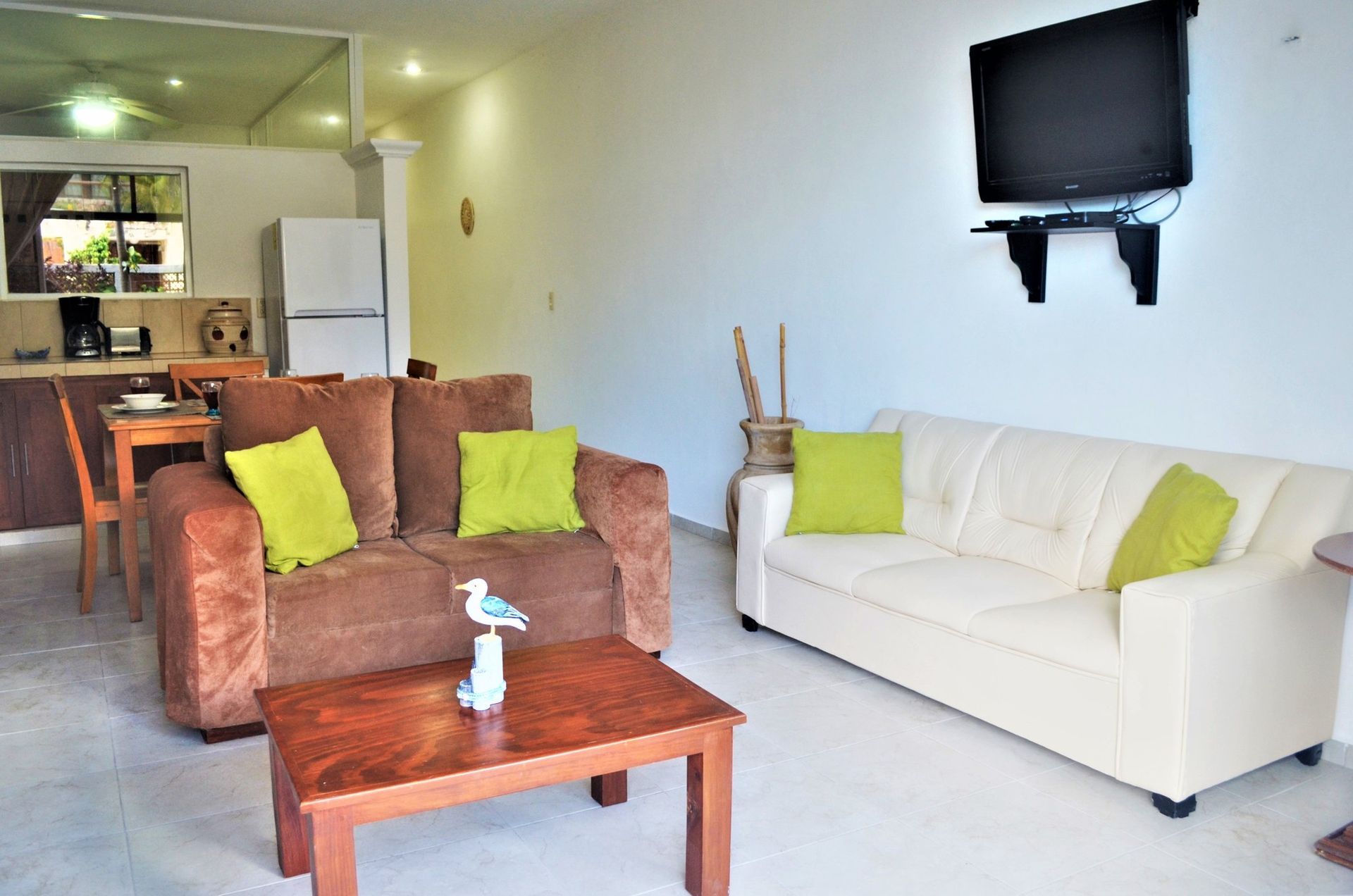 Living room with two sofas, coffee table, TV, and small dining area; neutral colors.