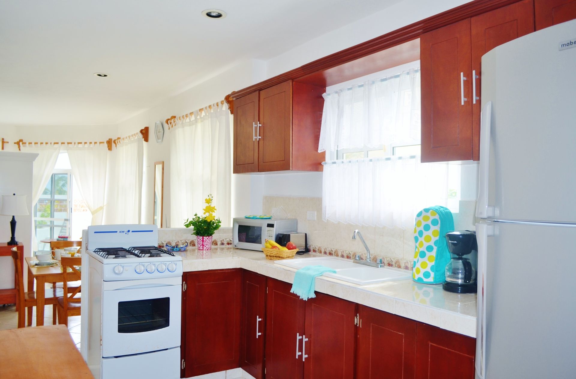Kitchen with red cabinets, white appliances, and a window above the sink.