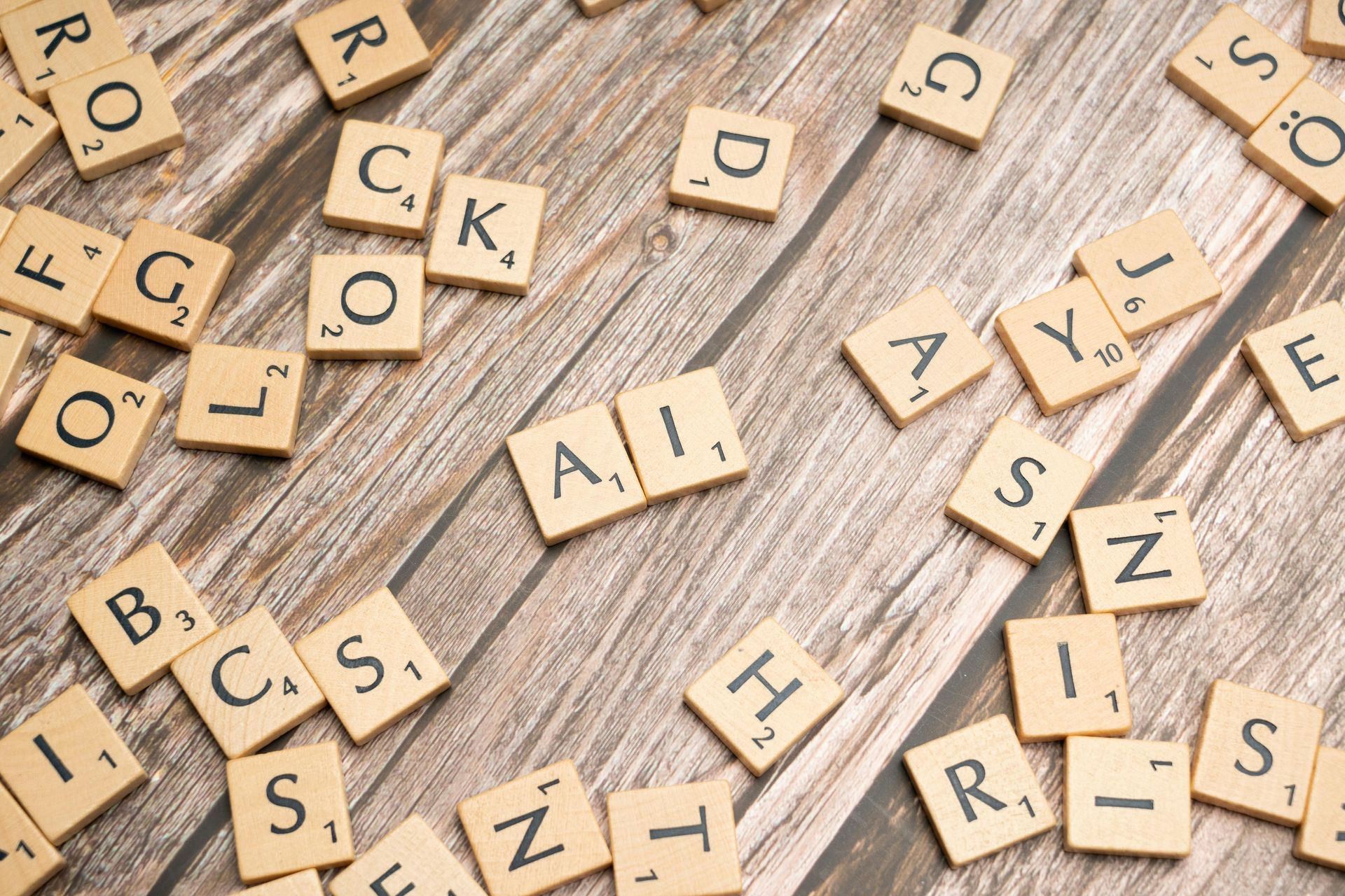 Scattered Scrabble-style letter tiles on a light wooden surface