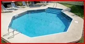 An octagonal swimming pool with stairs and chairs around it.
