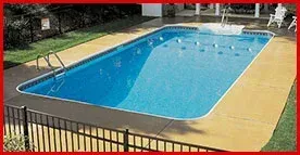 A large swimming pool surrounded by a fence in a backyard.
