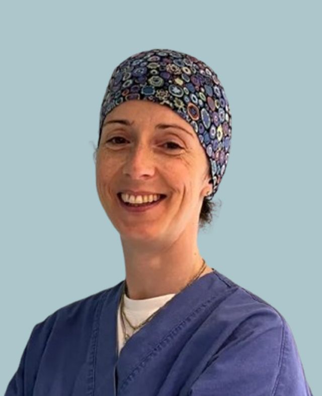 Una donna che indossa un camice e un cappello sorride alla telecamera